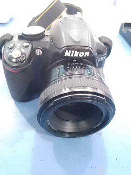 Camara Fotografica Profesional Marca Nikon Modelo D3100 Acc: CargadorLente 50mmCon Cinta Comentario: Lente De La Tapa Cuvierto Con Un Film